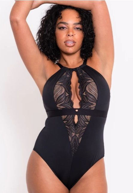 A woman is wearing a black bodysuit with a plunging neckline