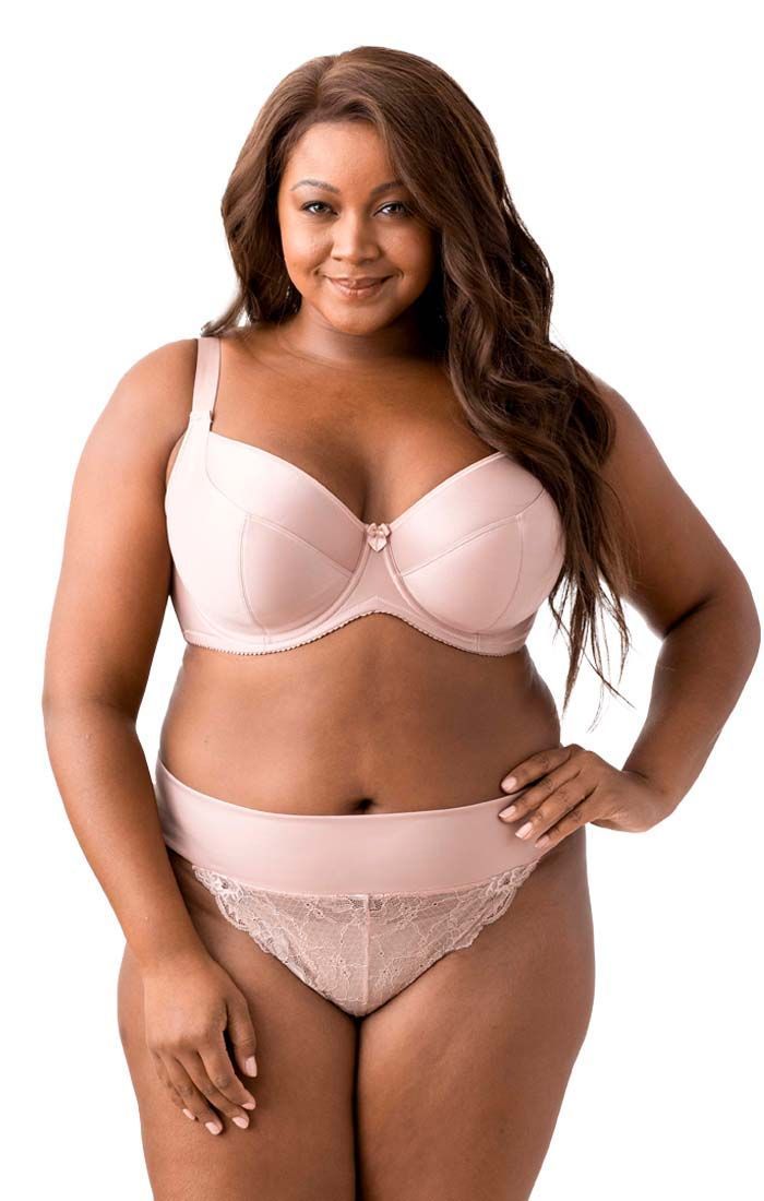 A plus size woman is wearing lingerie and smiling.