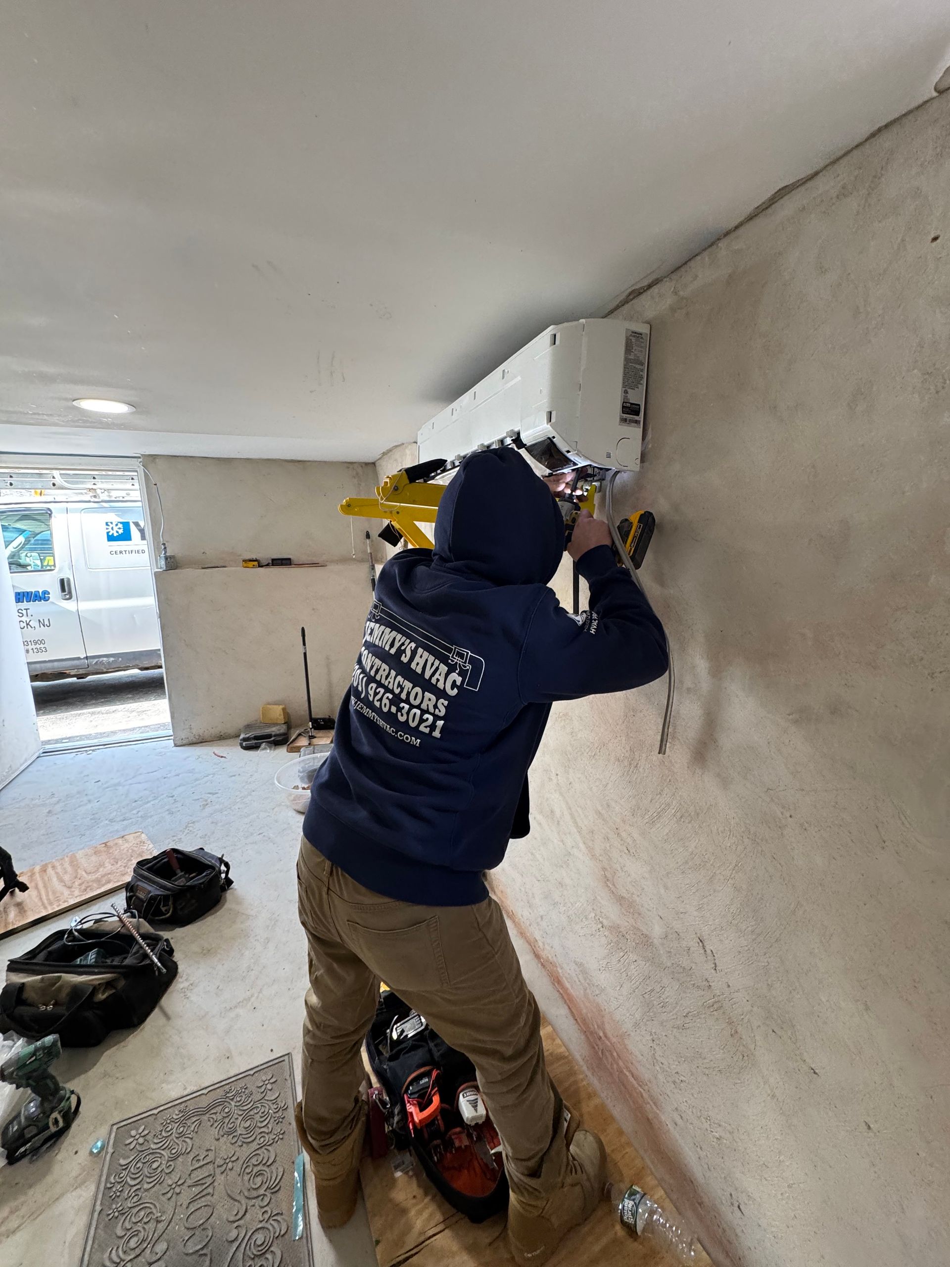 A man in a blue hoodie is working on a wall.
