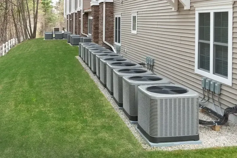A row of air conditioners are lined up on the side of a building.