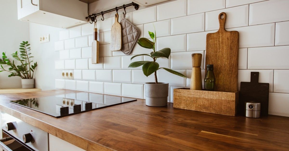 A dark wood kitchen countertop. Several items are on the counter, such as a cutting board and a potted plant.