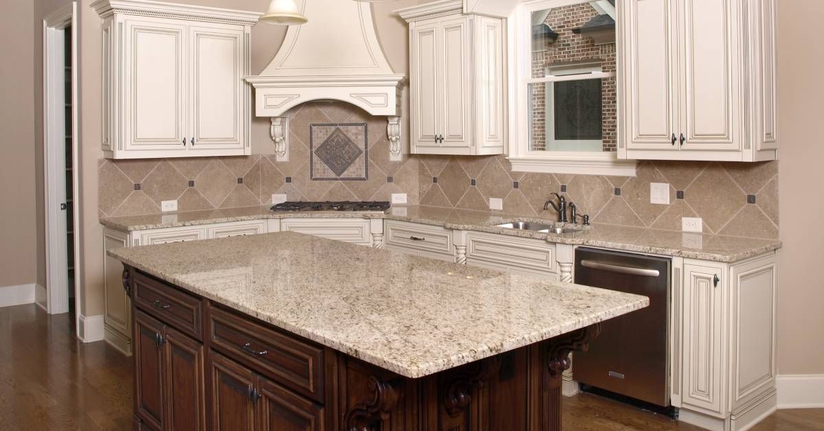 A clean kitchen with granite countertops, dark wooden floors, and elegant cabinets. The countertops are empty.