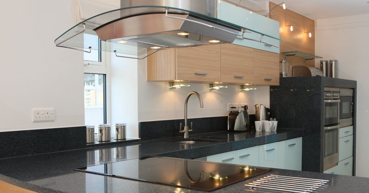 A large kitchen with a massive L-shaped countertop in it. The countertop is clean and dark in color.