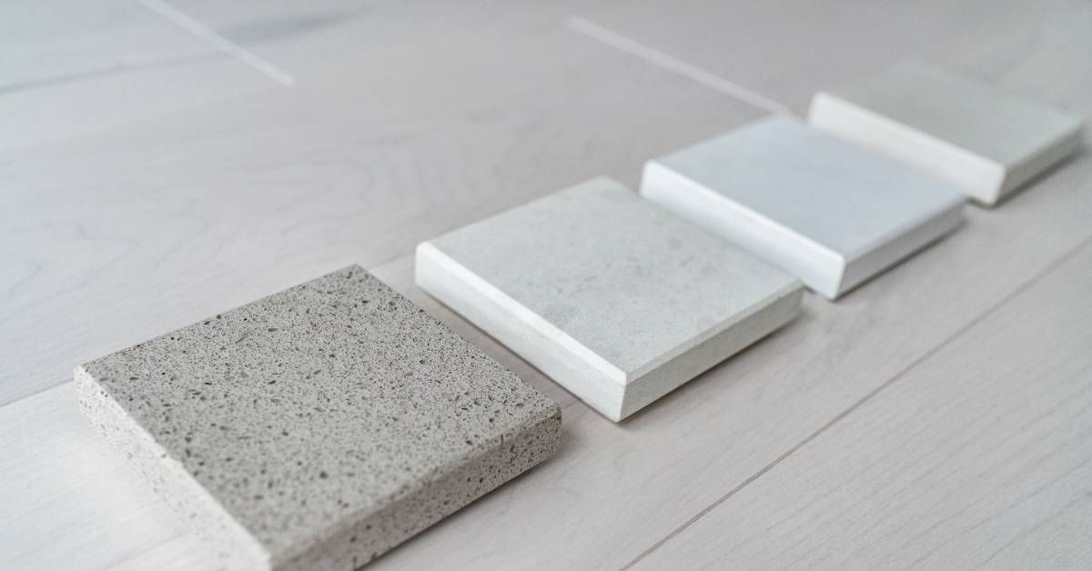 Four different quartz samples precisely cut into square blocks are lying on the white floor inside a