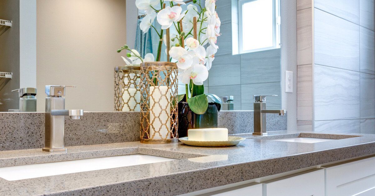 A residential bathroom with a shower and clean countertop surface. Colorful flowers are in a vase on