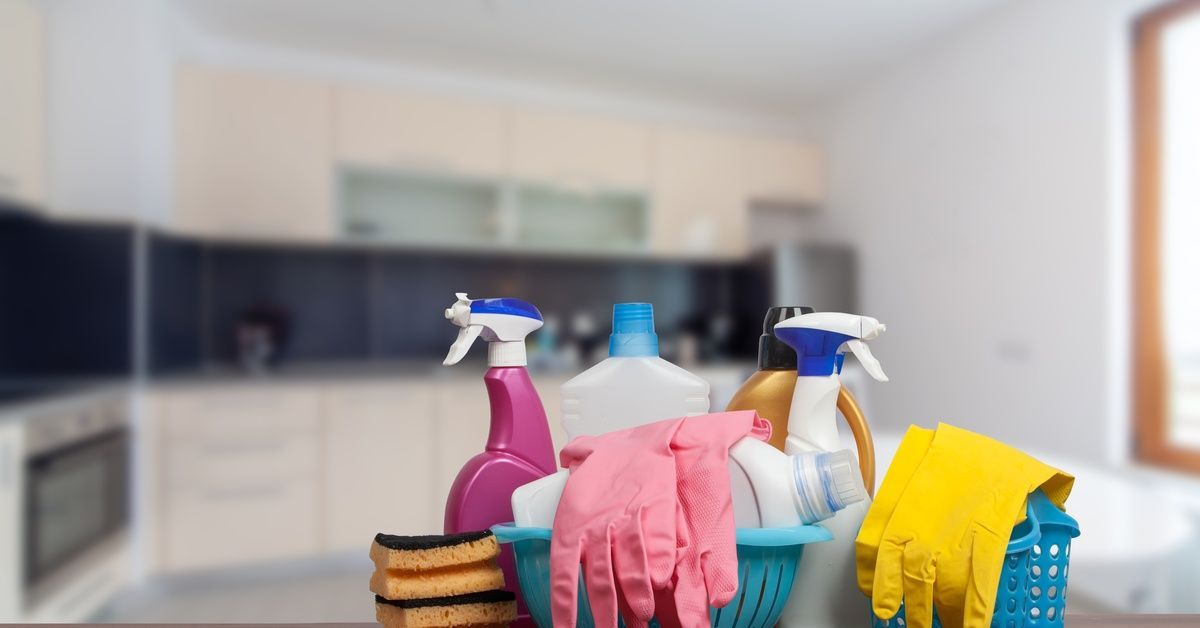 Spray bottles sitting next to three blue baskets full of gloves.