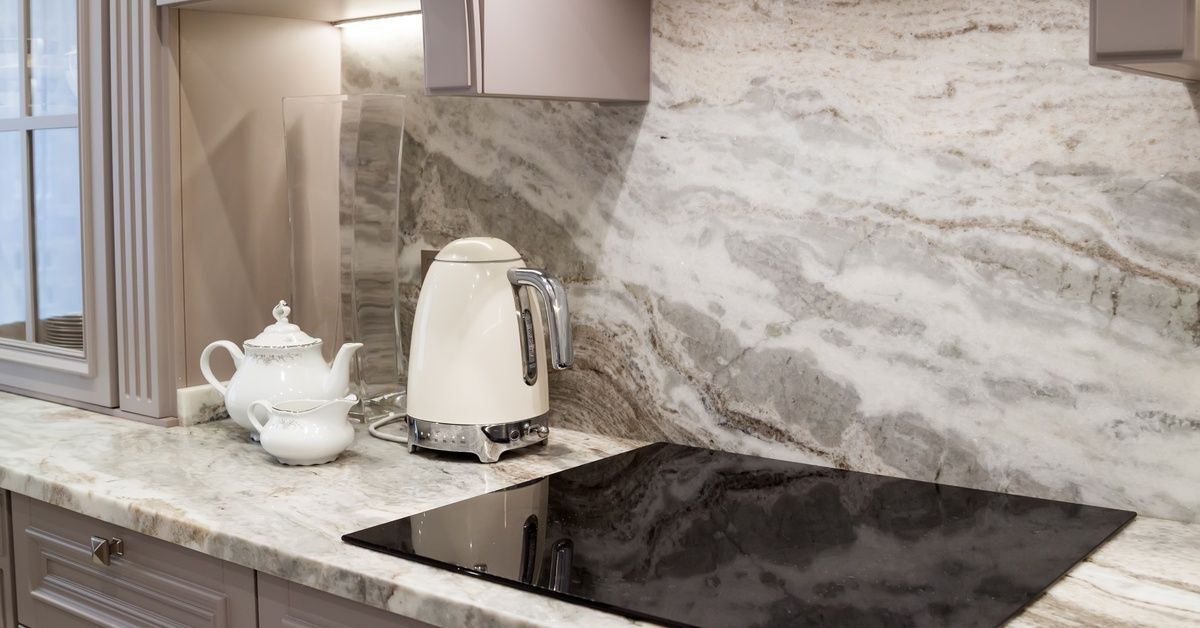 A quartz countertop in a kitchen with a built-in stove. Three white kitchen appliances are on the countertop.
