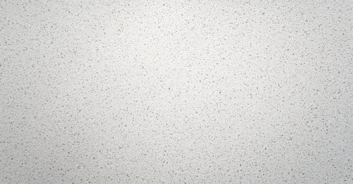 A white countertop that is made of solid surface materials. The solid surface counter has lightly colored specks in it.