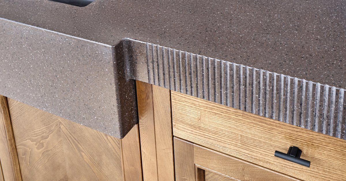 A solid surface countertop that is dark in color and installed on top of wooden cabinets and drawers