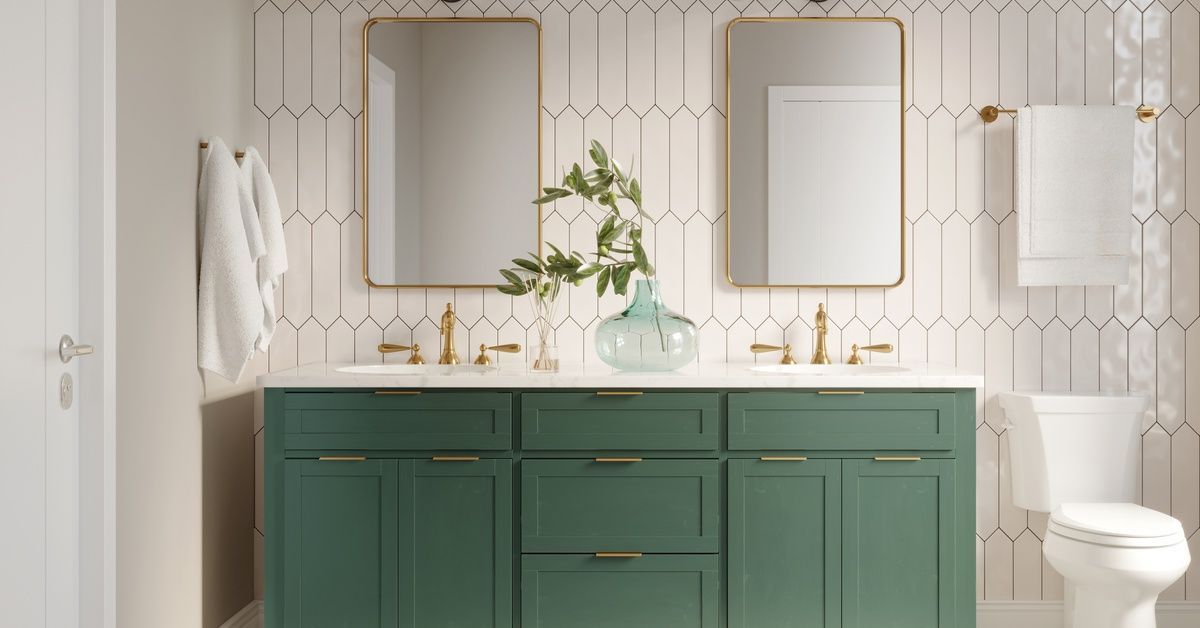 A green vanity installed in a bathroom with decorative patterns all over the wall. Two mirrors are a