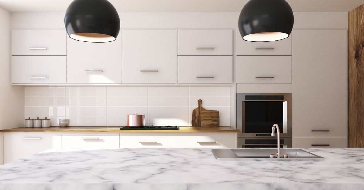 A residential kitchen with wooden countertops along the wall. A marble island is in the center of the room.
