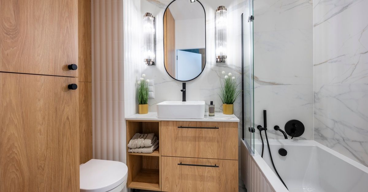 A bathroom with white walls and a white vanity. The vanity has two green potted plants on top of it.