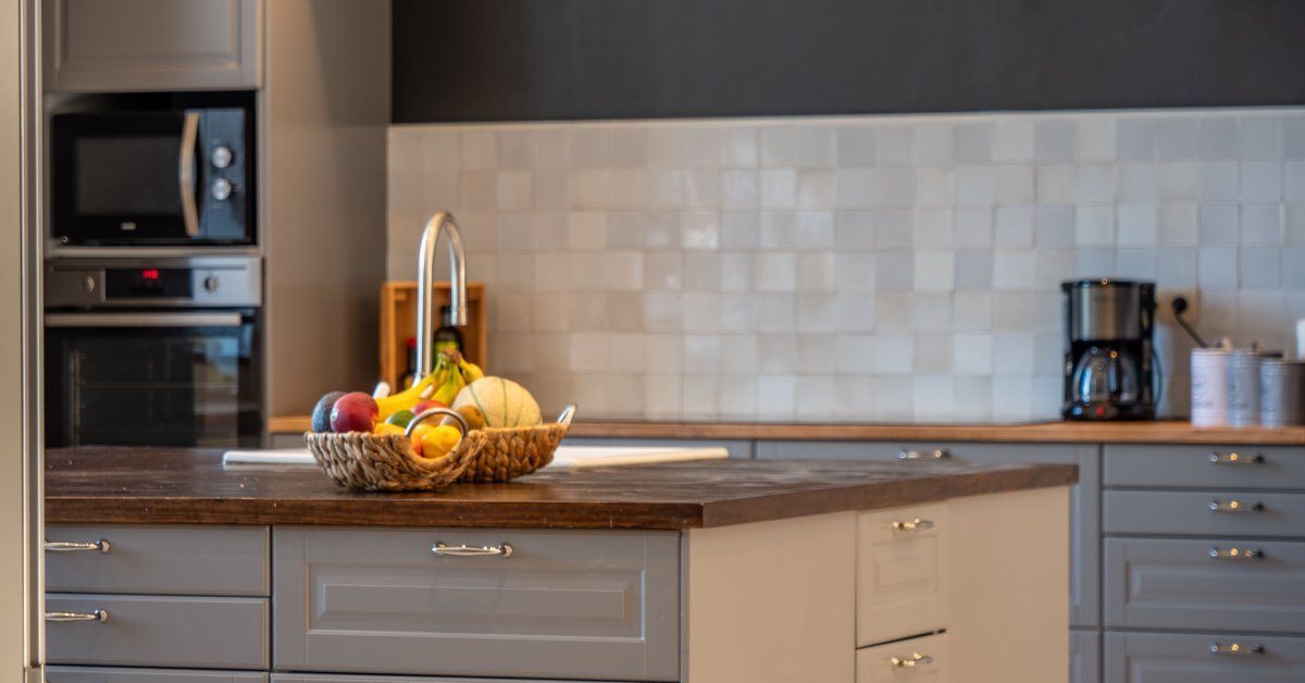 A kitchen with dark wooden countertops and neutral tiles on the wall.