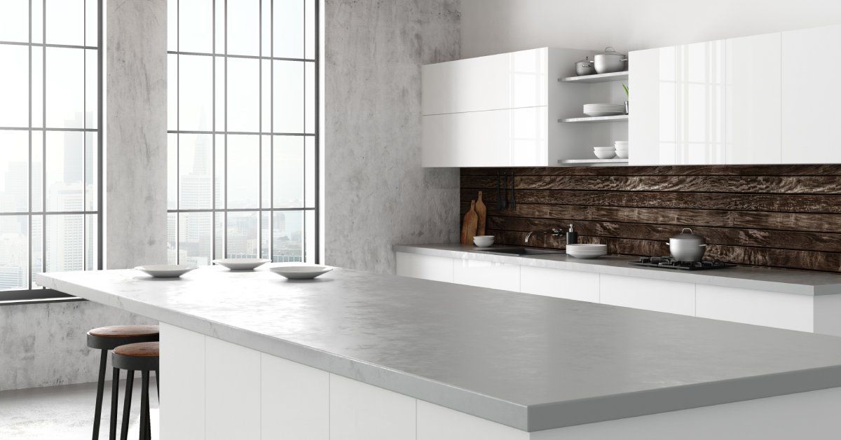 A massive kitchen with two large windows. An island with a wide gray countertop is in the center of the room.