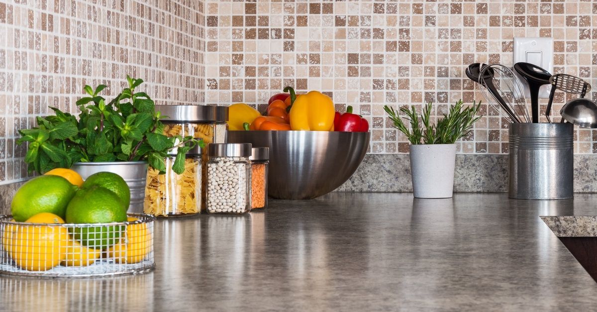 Containers full of fruit, herbs, and assorted ingredients neatly organized on a residential stone kitchen countertop.