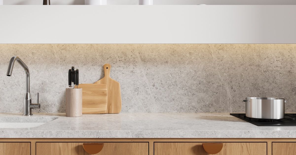 A quartz kitchen countertop on top of wooden cabinets. A sink and stove are installed in the counter