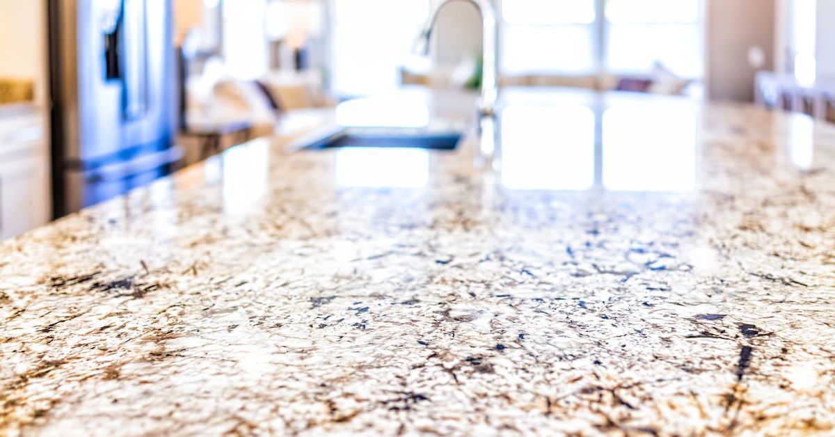 A granite countertop with a faucet installed on it. The countertop is in the middle of a residential kitchen.