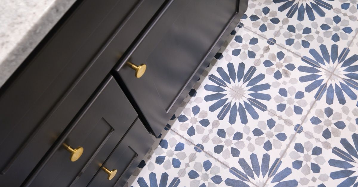 A bathroom vanity with black cabinets underneath. The vanity is bult on a tile floor with floral patterns.