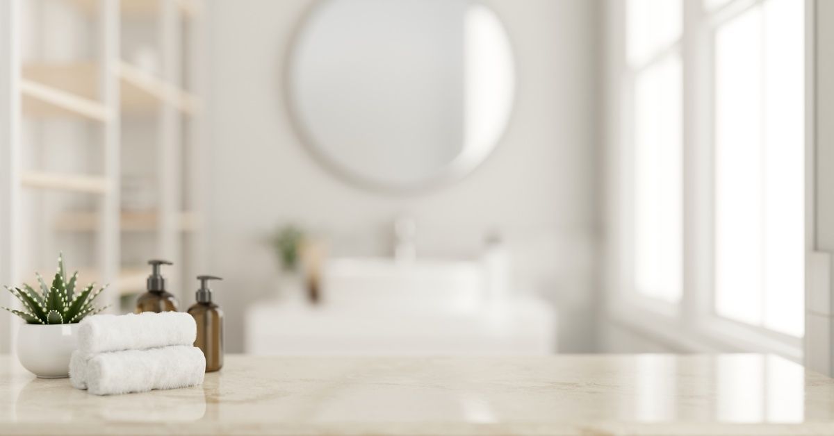 Three hand towels, two soap dispensers, and one potted plant sitting on the surface of a bathroom vanity.