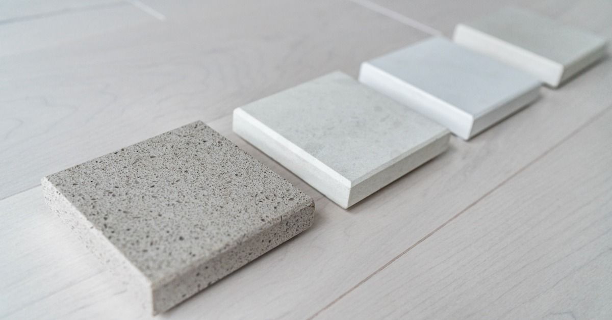 Four quartz countertop samples lying on a wooden floor. All counter four samples are different color