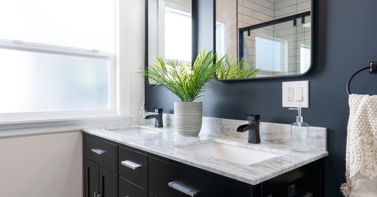 A double bath vanity with a potted plant on its counter. Two square mirrors hang above the sinks on the vanity.