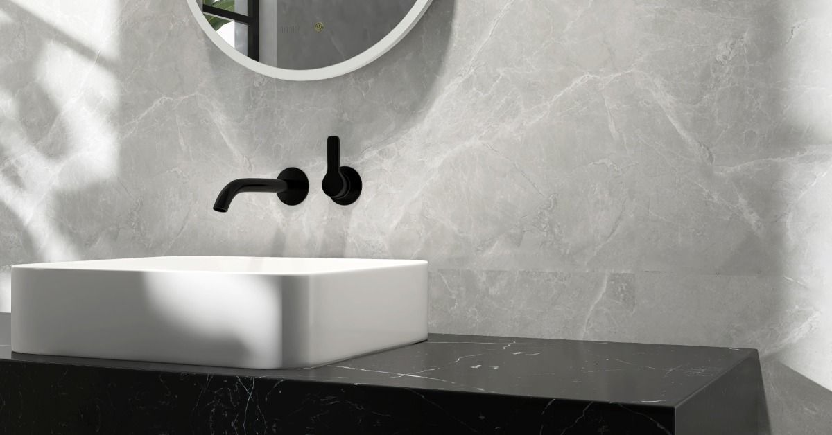 A single bath vanity in a dark bathroom. A black faucet and round mirror are installed on the wall above the sink.