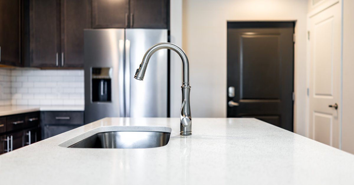 A white quartz kitchen countertop covering an island with a built-in stainless steel kitchen sink.