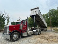 A red dump truck is parked in a gravel lot.