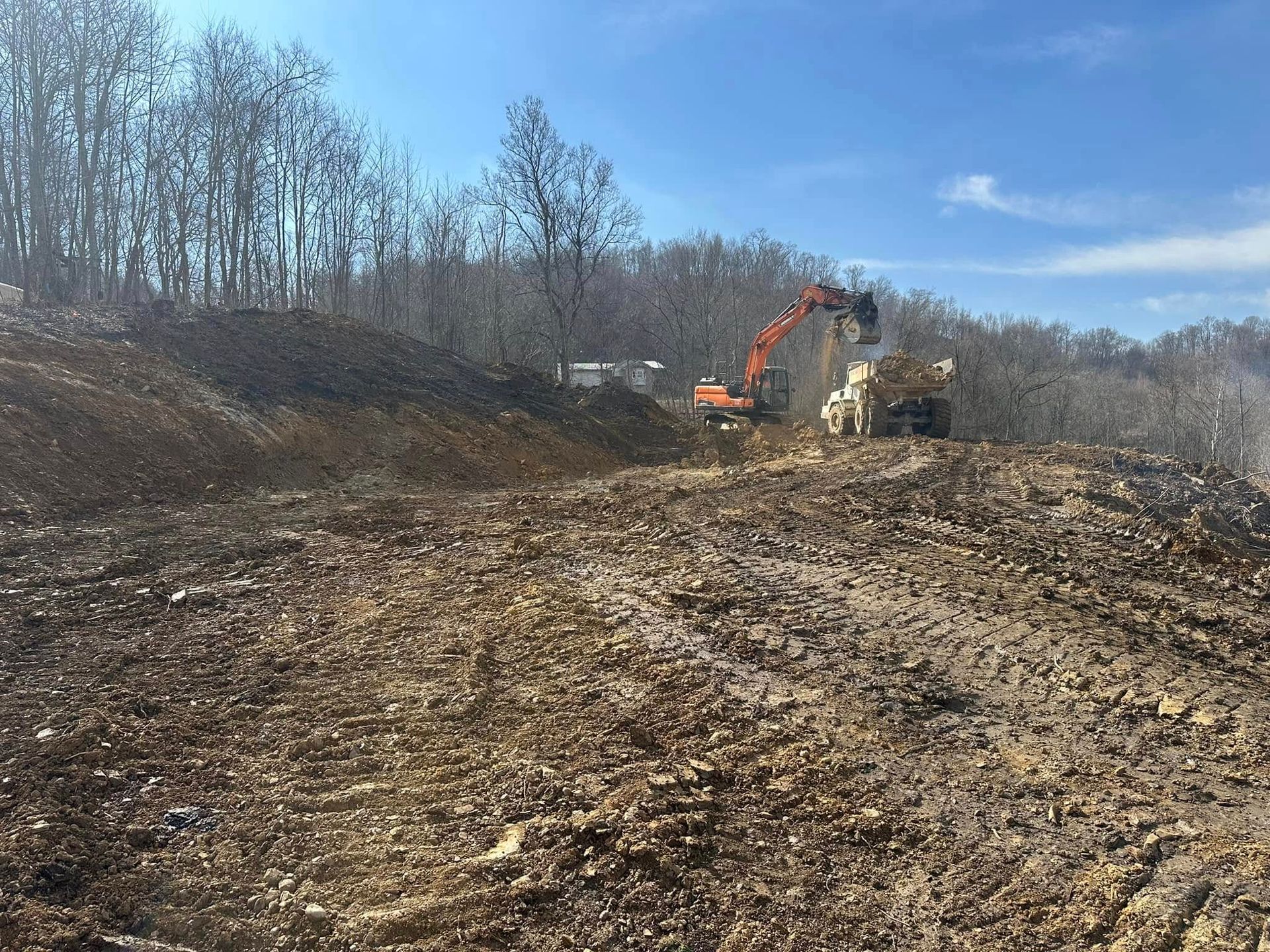 A bulldozer is moving dirt in a field with trees in the background.