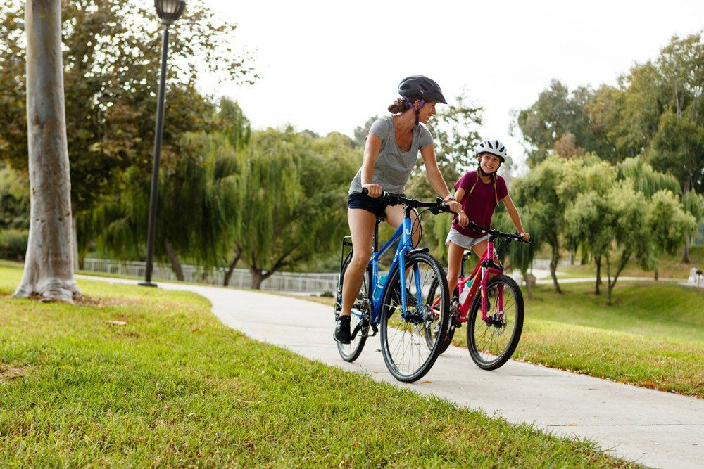 Two women riding on a Blue and Red Hybrid Bikes