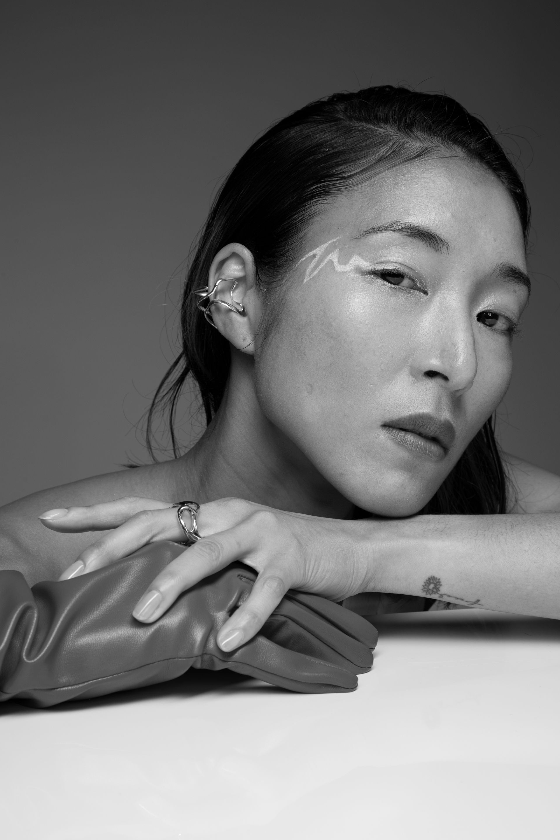 Woman with makeup, leaning on a white surface with one hand in a red glove.