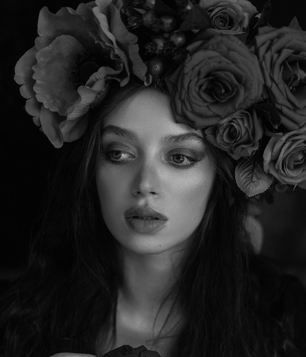 Woman with flower crown, looking away. Black and white portrait.