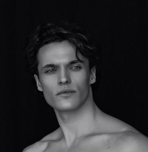 Man with wavy dark hair, looking off-camera. Black and white, head and shoulders portrait.