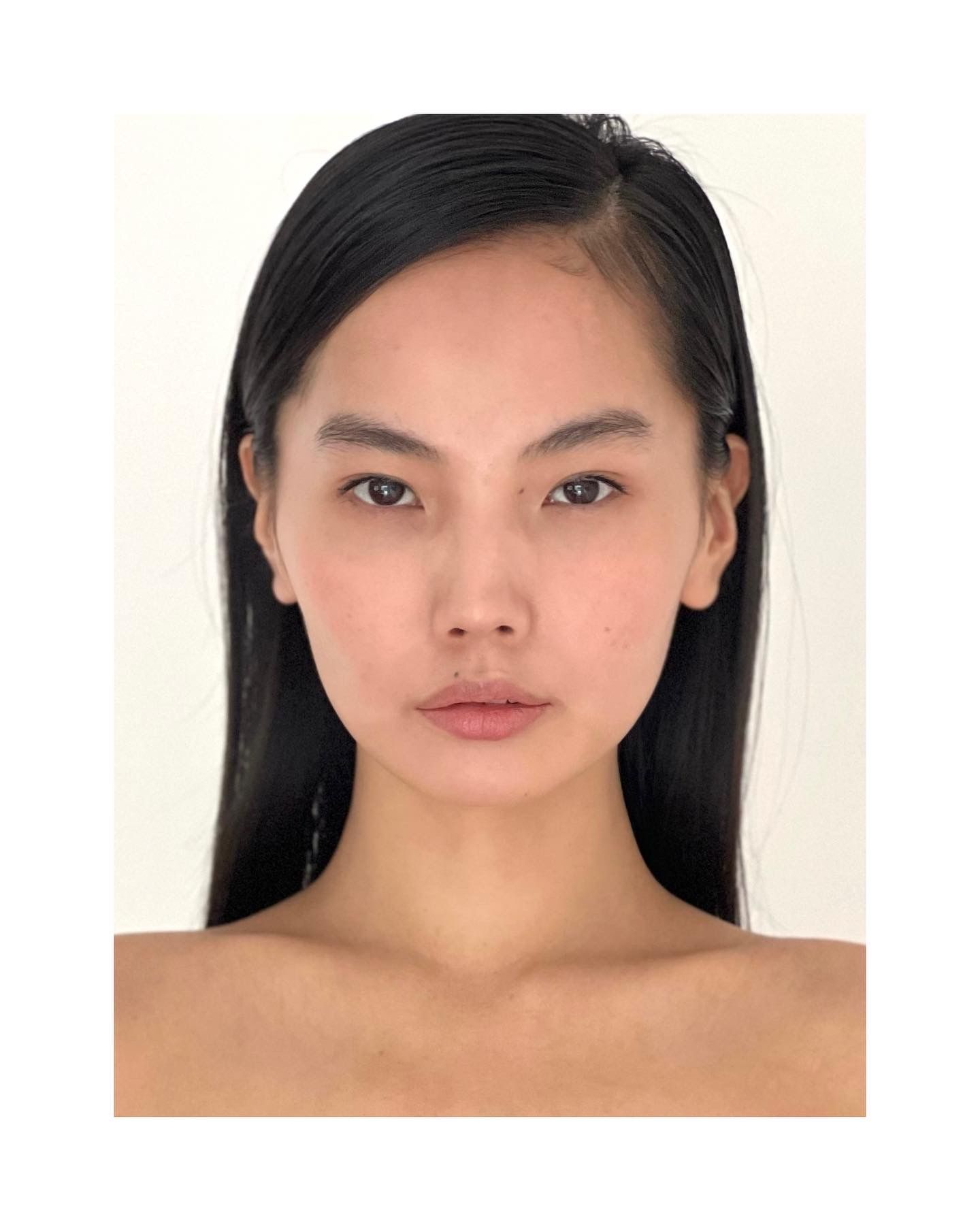 Person with dark hair and neutral expression, against a light background.