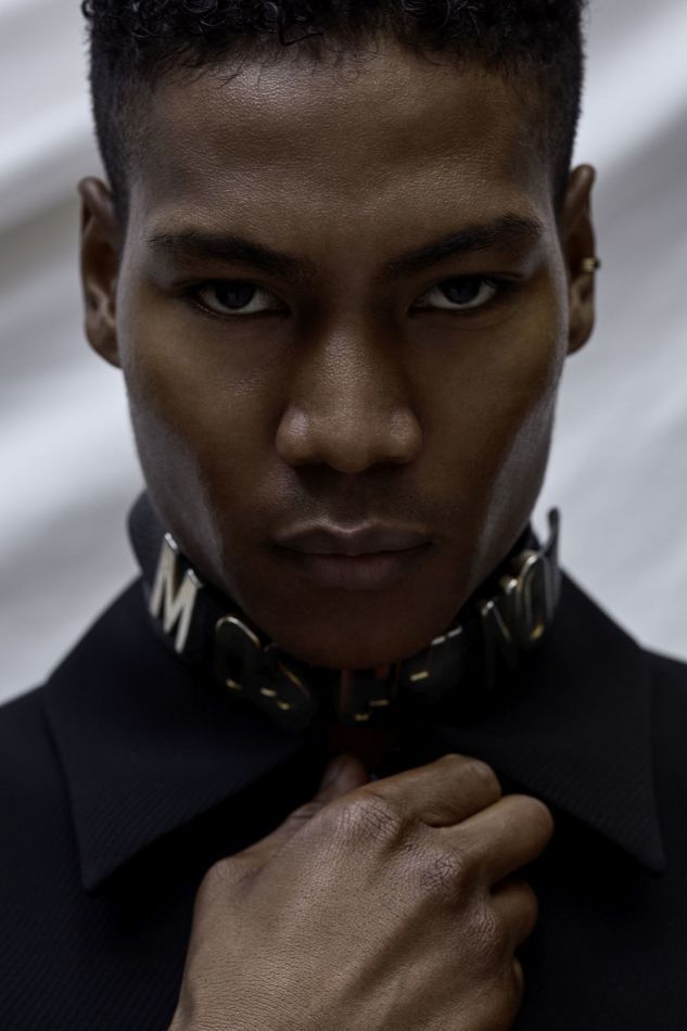 Man in black collared shirt and choker; looks directly at the camera.