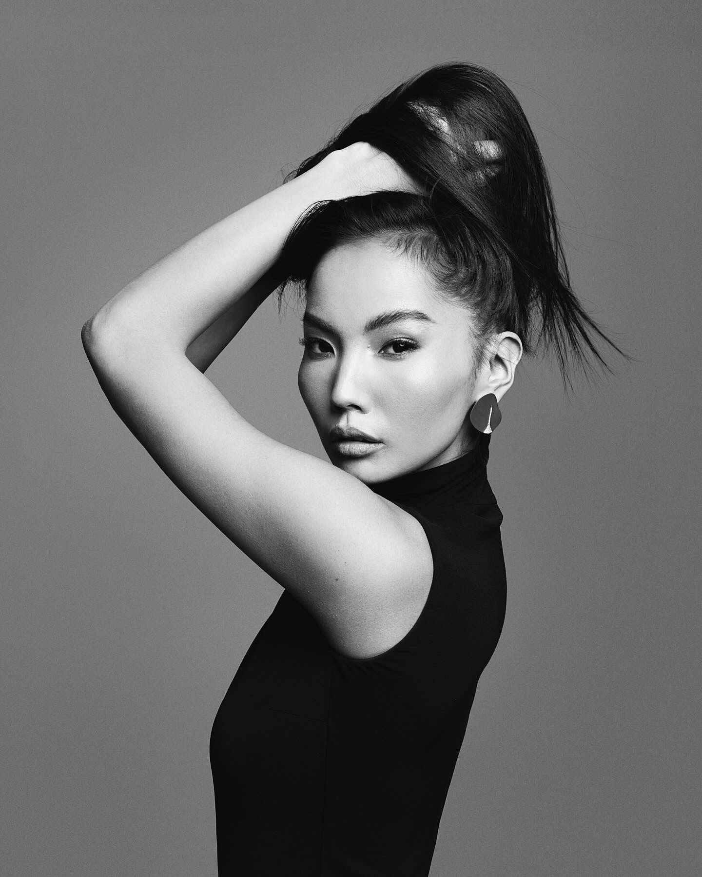 Woman with dark hair in a high ponytail, wearing a black turtleneck, and looking at the camera.