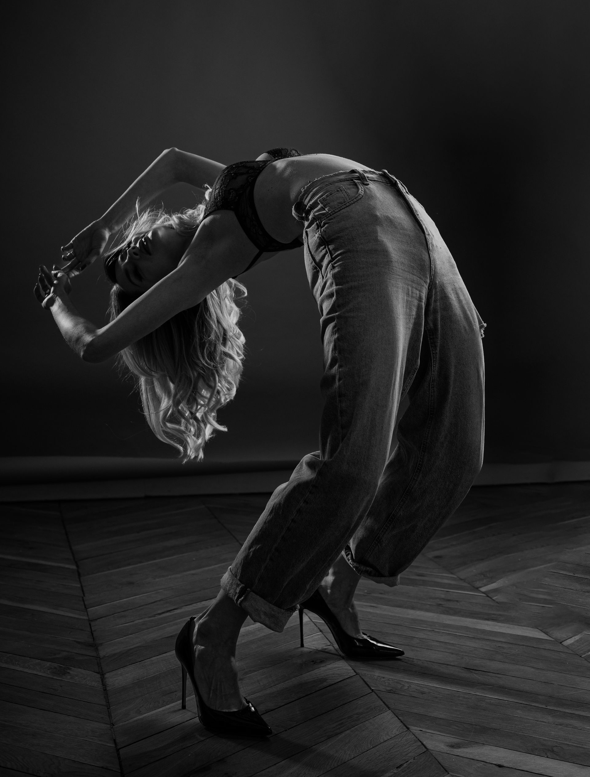 Woman in heels, arched back, wearing a bra and sequin pants.