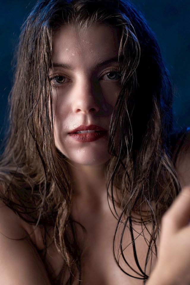 Woman with wet hair and a serious expression, dark background.