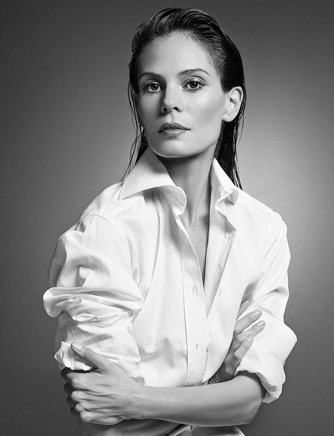 Woman in white button-up shirt, arms crossed, wet hair, serious expression, studio portrait.
