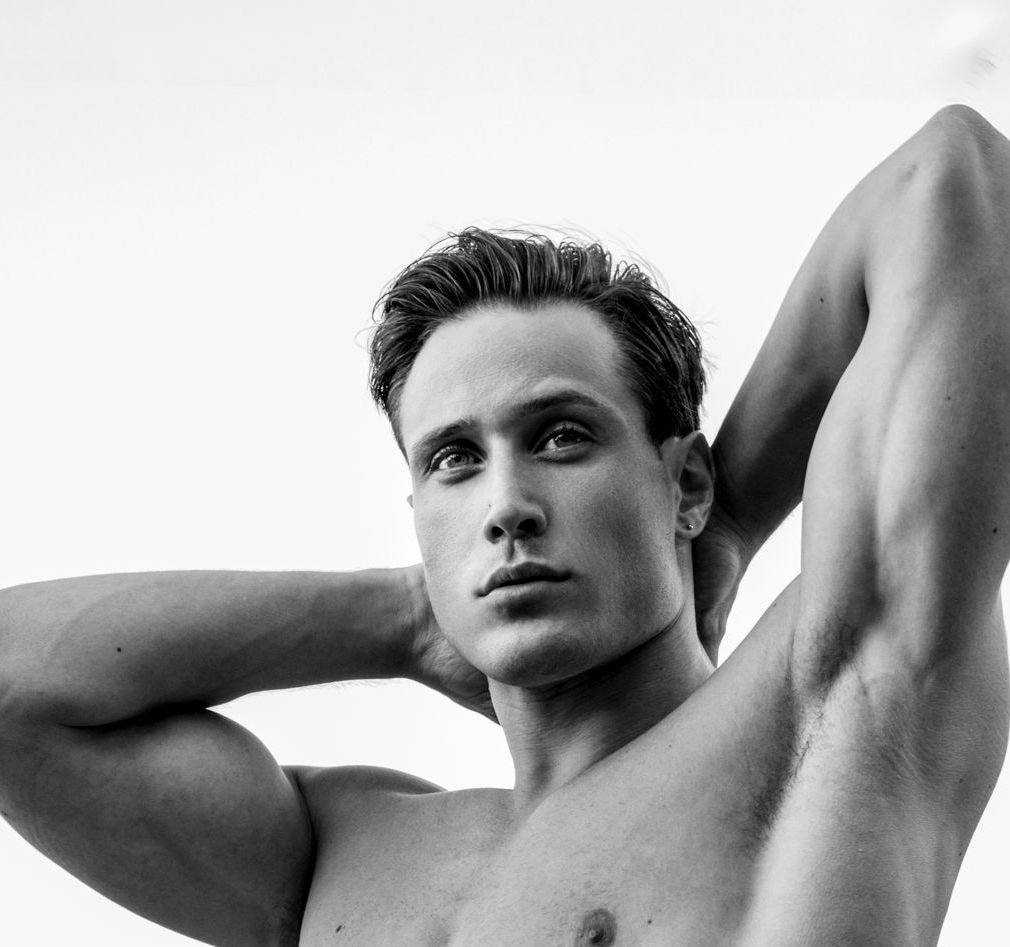 Man with arms behind head, looking up. Monochrome.