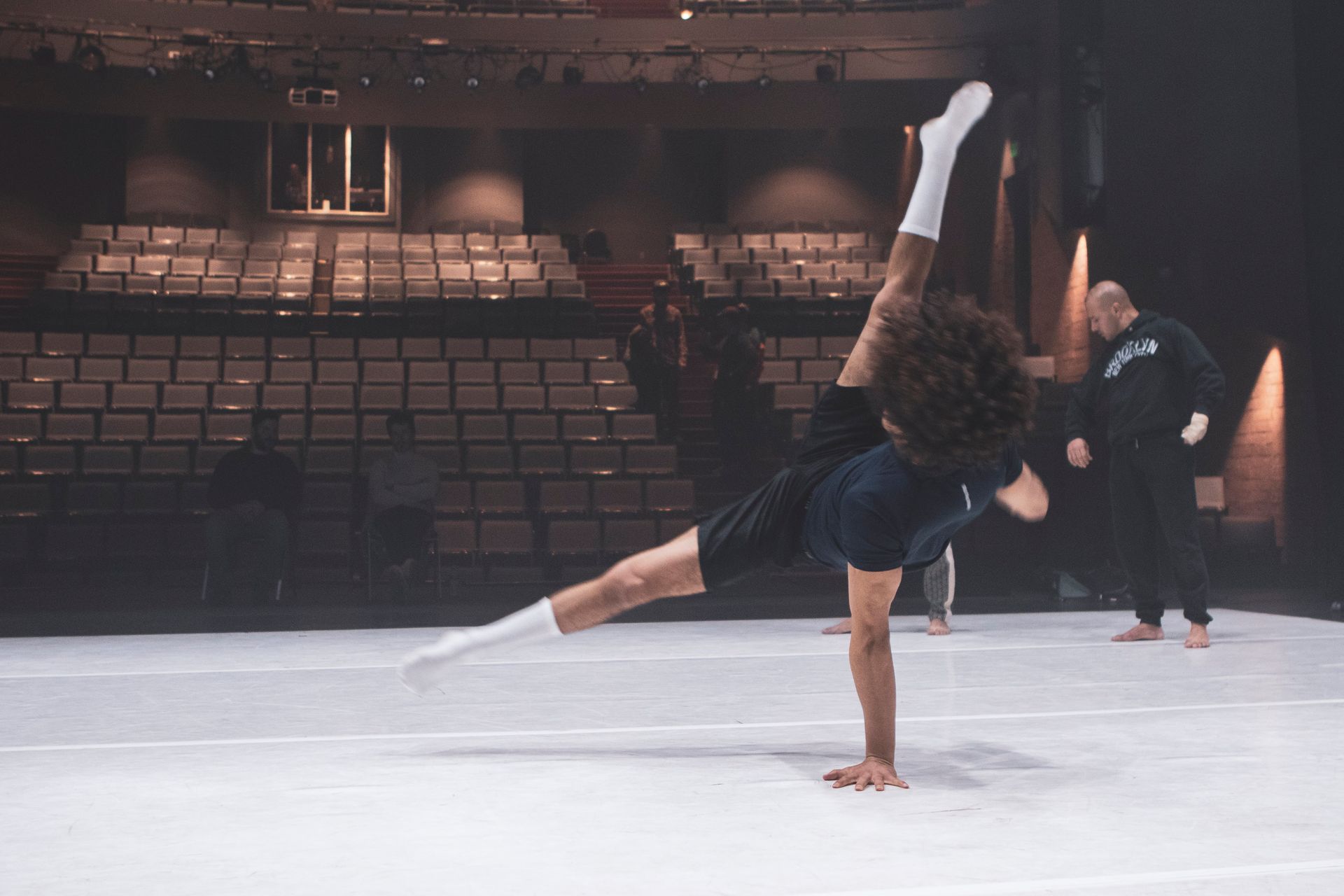 A dancer balances in a handstand split on a stage.
