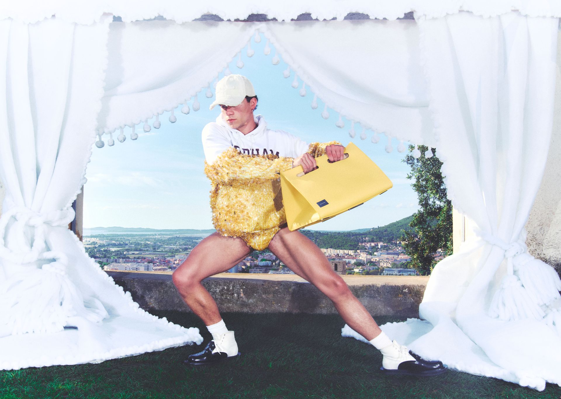 Man in athletic wear and gold costume posing on a terrace with cityscape backdrop.