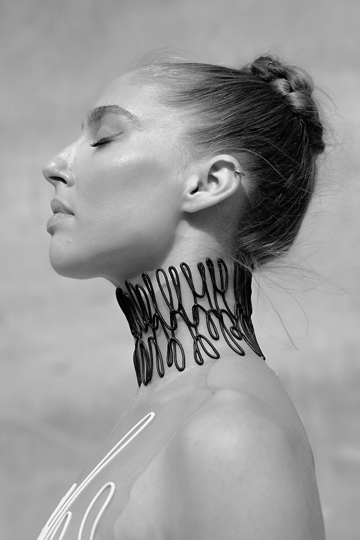 Woman with eyes closed, wearing a beaded choker, outdoors.