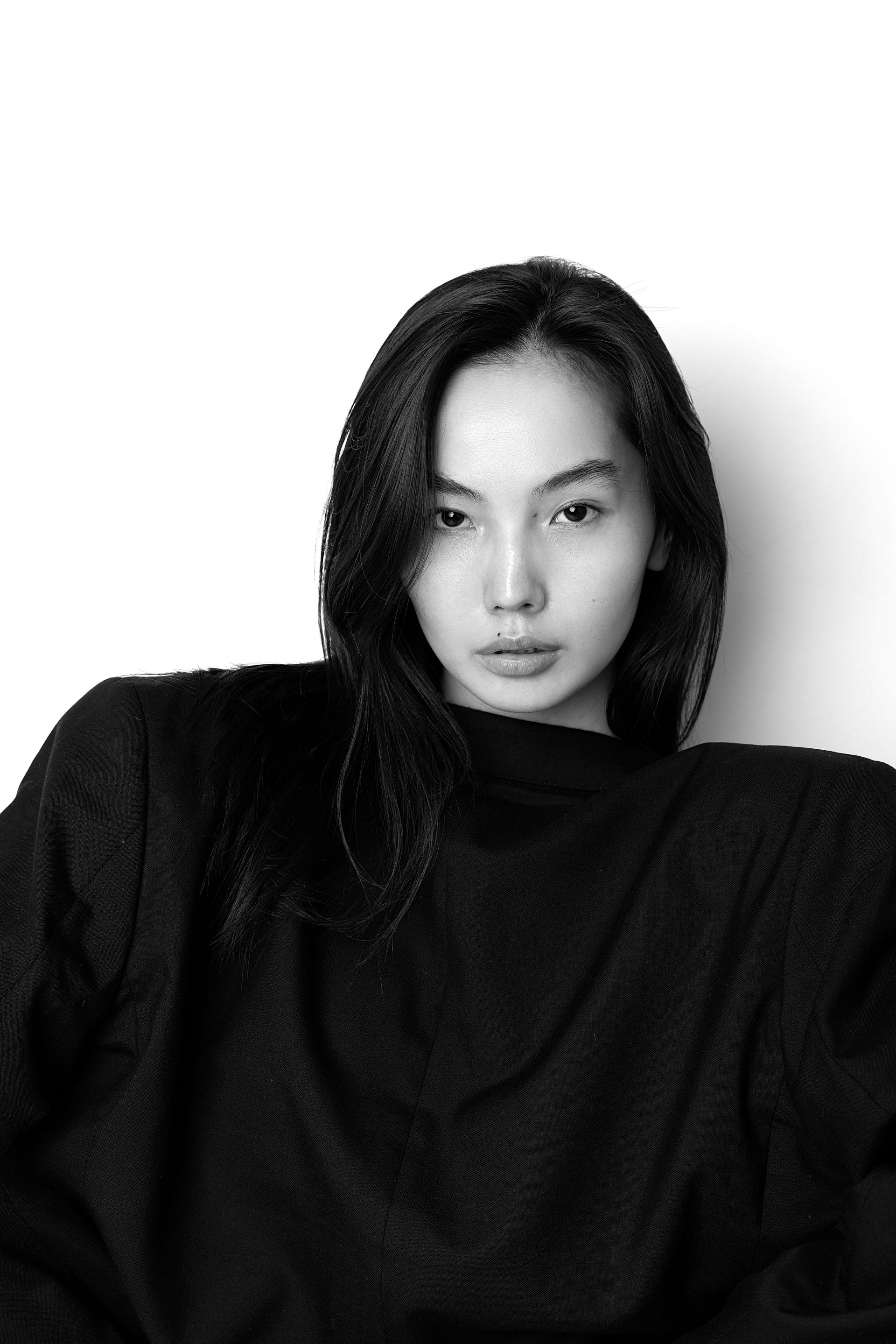 Woman in black top, looking directly at the camera, against a white backdrop.