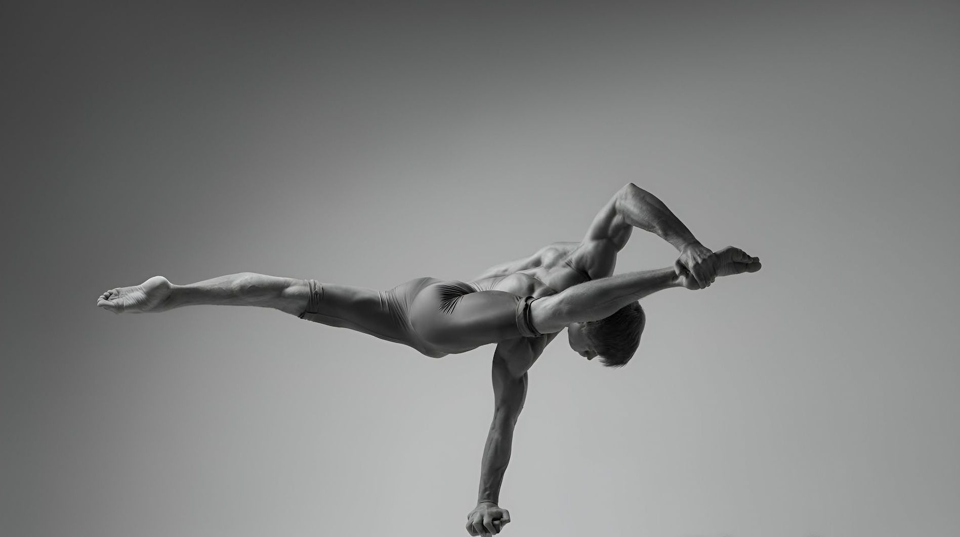 Man balancing on one arm, body outstretched, against a plain background.