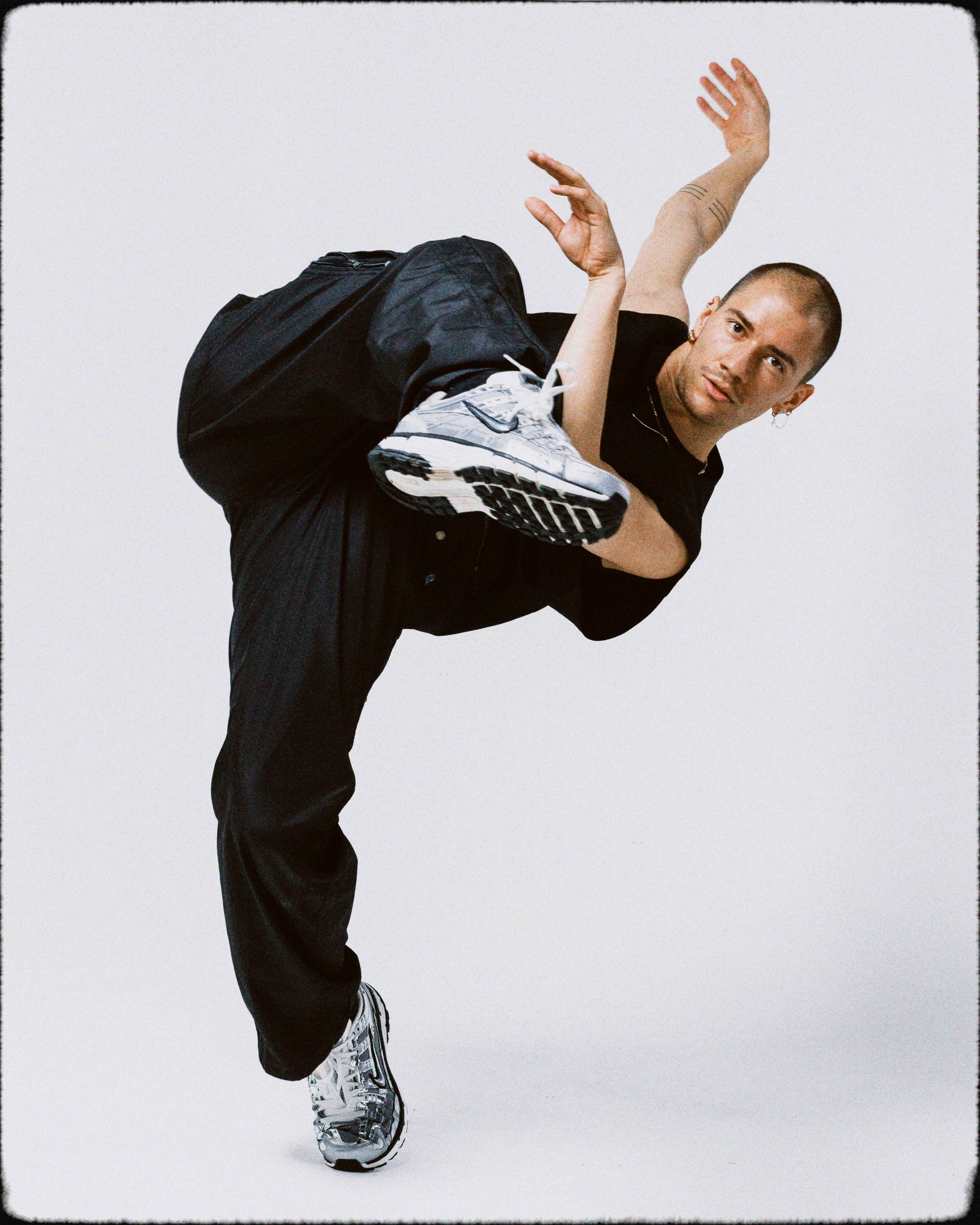 Dancer in black outfit performs acrobatic move, balancing on one leg, arms extended.