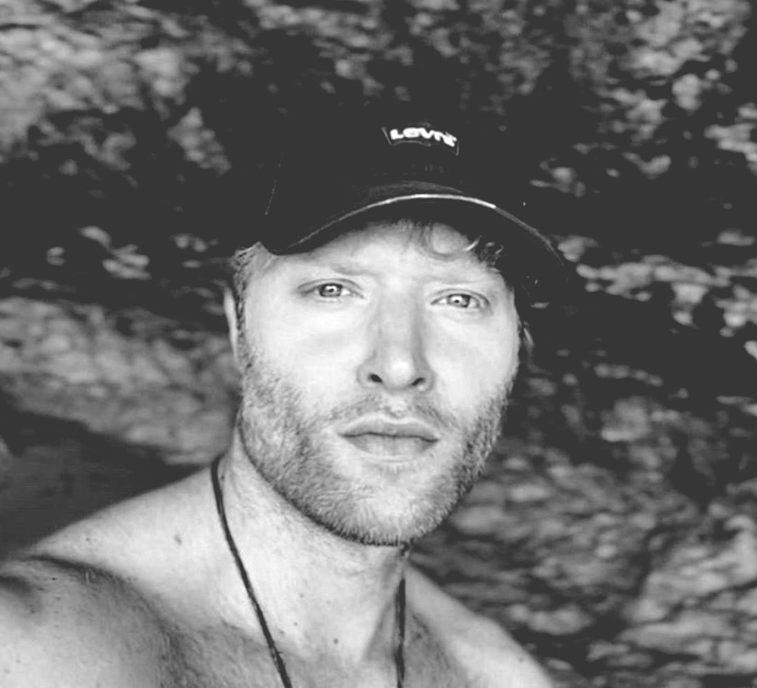Man with a beard wearing a Levi's baseball cap, outdoors in black and white.