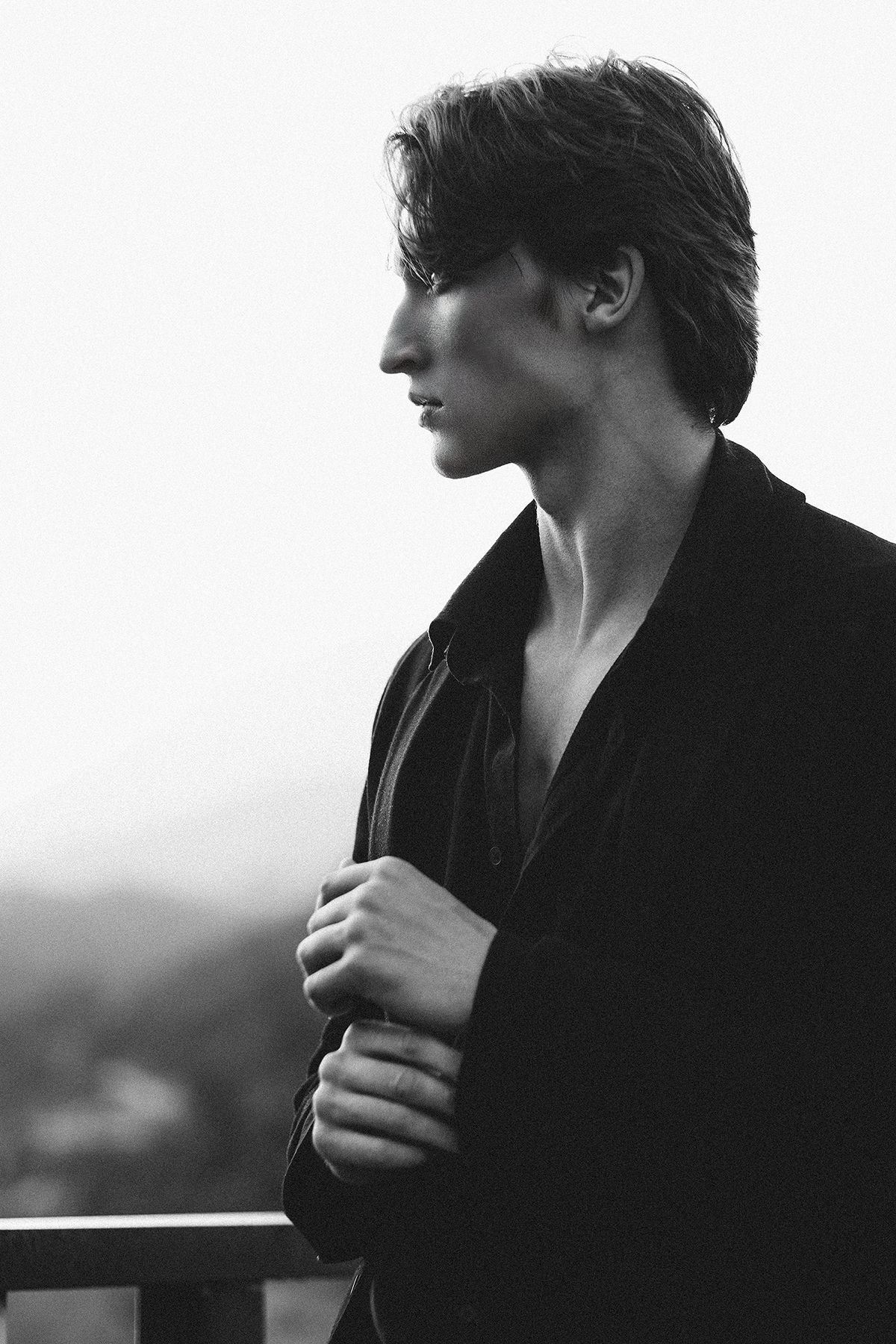 Man in dark jacket, looking away. Outdoors, shoulder-up shot.