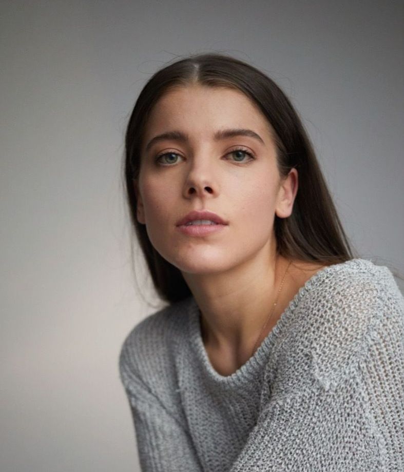 Woman in gray sweater, looking directly at the camera.