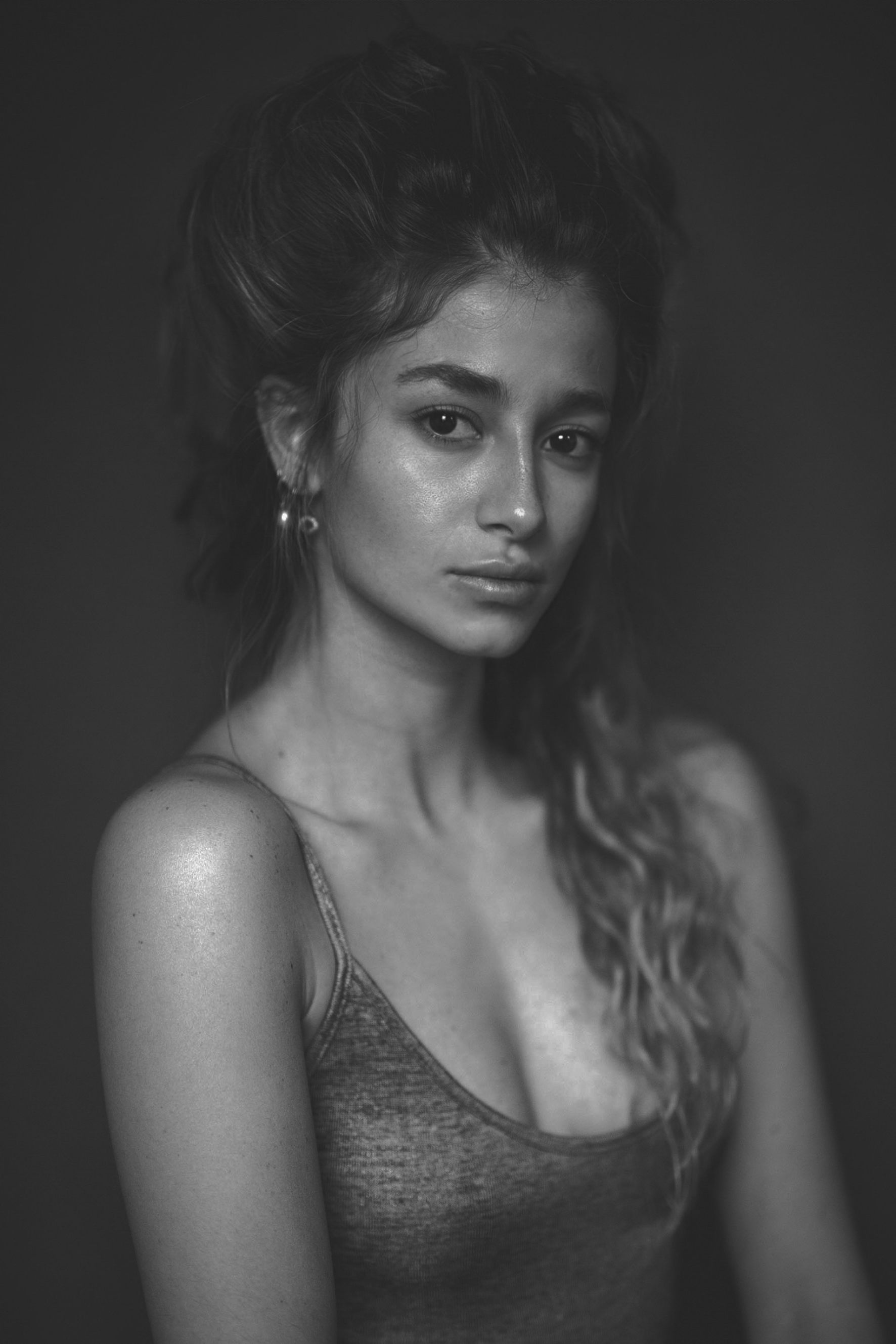 Woman with wavy hair in a metallic top, looking at the camera. Black and white portrait.